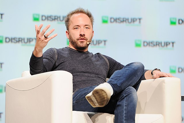 CEO Drew Houston speaks and sits in a cream chair while being interviewed at TechCrunch's Disrupt in San Francisco. 