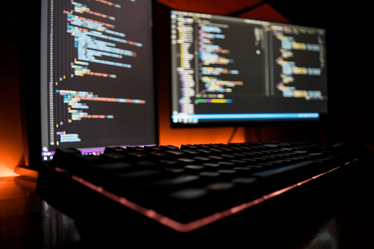 image of two computer monitors and keyboard with trunk-based development coding on the screens