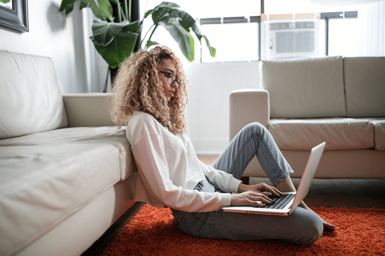 Image of woman sitting on floor typing on laptop